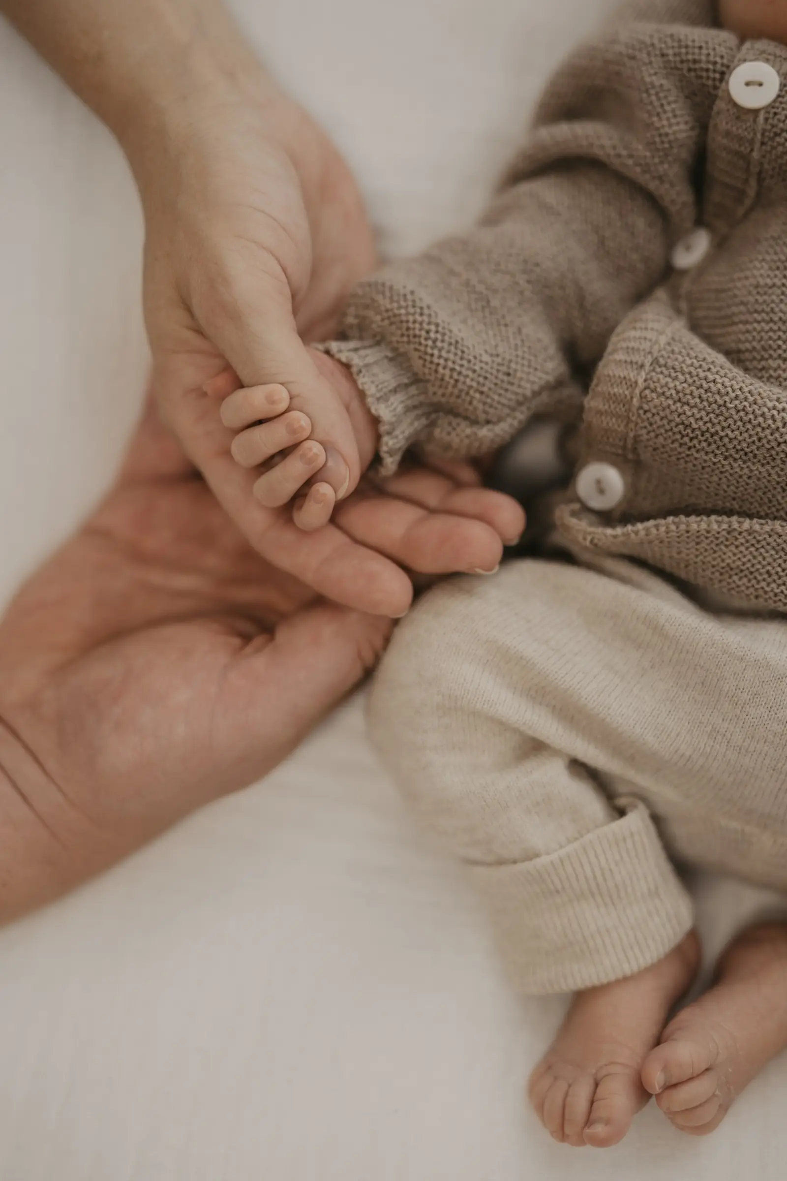 Elternhände halten die kleinen Füße des Babys