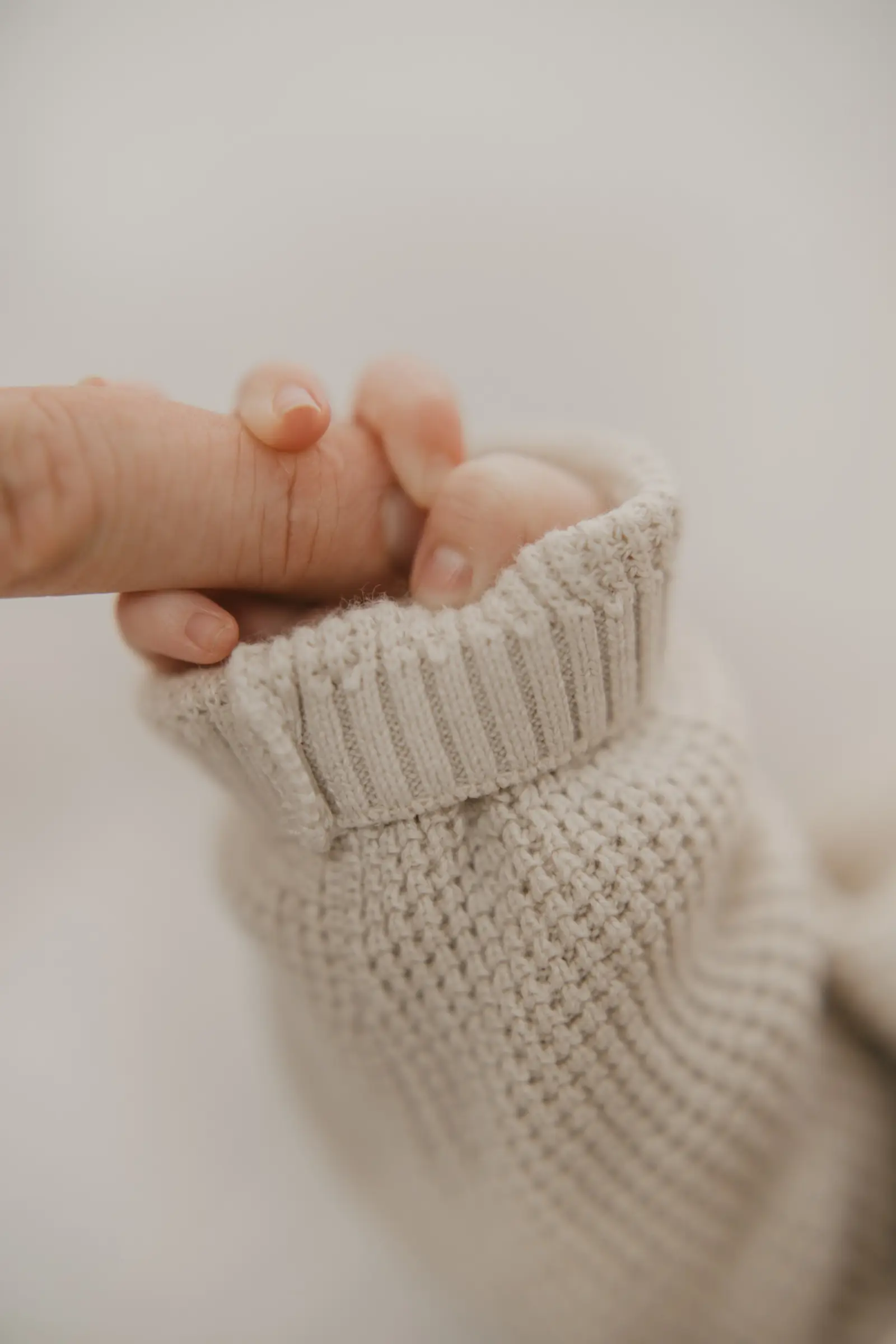 Detail: Babyfüße ragen aus einem Strickärmel