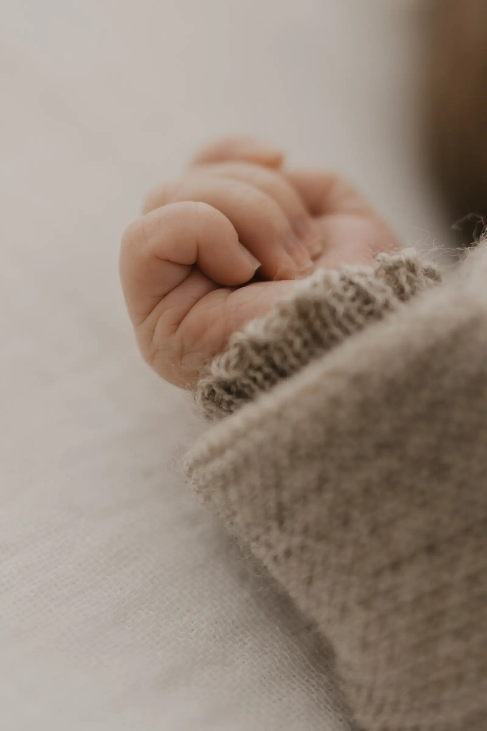 Detailaufnahme: kleine Babyhand in einem Strickärmel